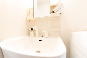 A bathroom with a white sink, a mirror, and a towel rack.