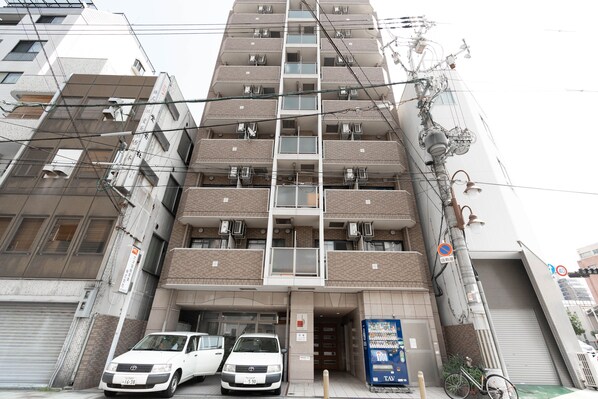 A multi-story residential building with a central staircase, air conditioning units, and a gated entrance.