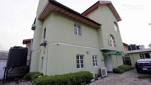A two-story building with a green facade, multiple windows, and satellite dishes on the roof. - Greenland Suites (Lagos)