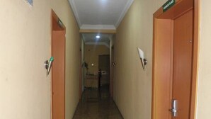 A hallway with wooden doors, each labeled with a room number. The walls are beige, and the floor is tiled. - Greenland Suites (Lagos)