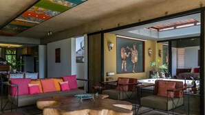 Una sala de estar moderna con una mesa de centro de madera, un sofá con cojines coloridos y un cuadro grande en la pared.