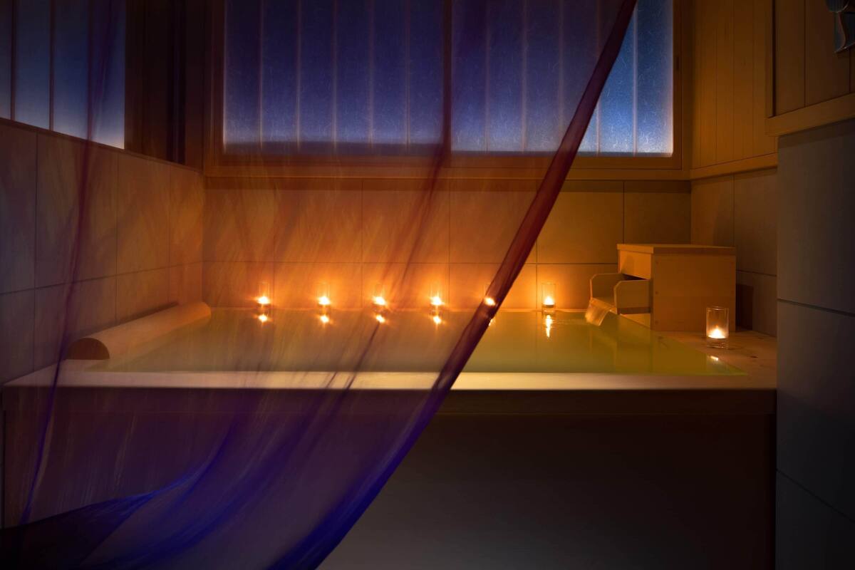 Une salle de bain moderne avec une baignoire, des bougies et une fenêtre.