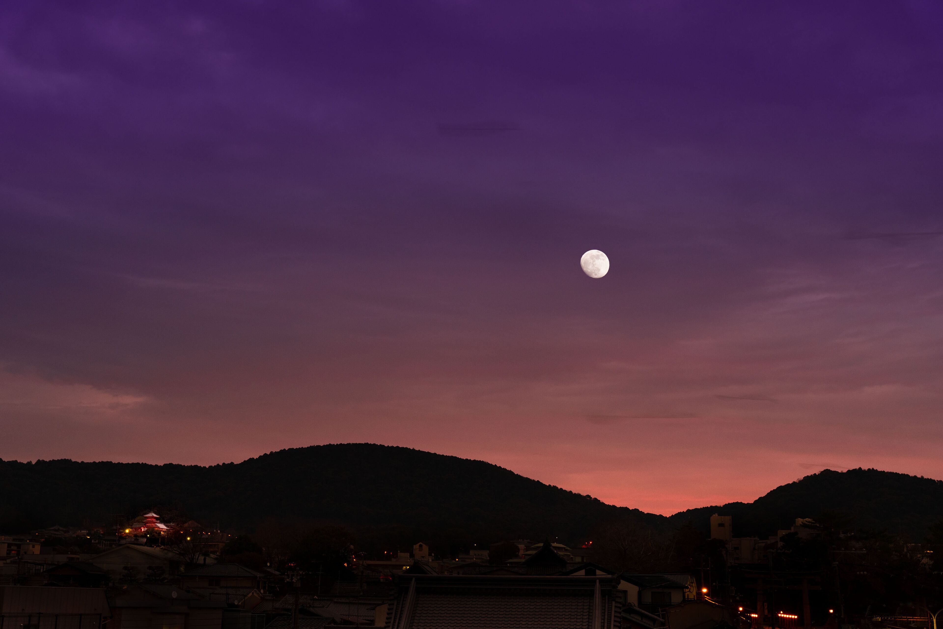 Cielo nocturno con luna visible sobre un paisaje montañoso.