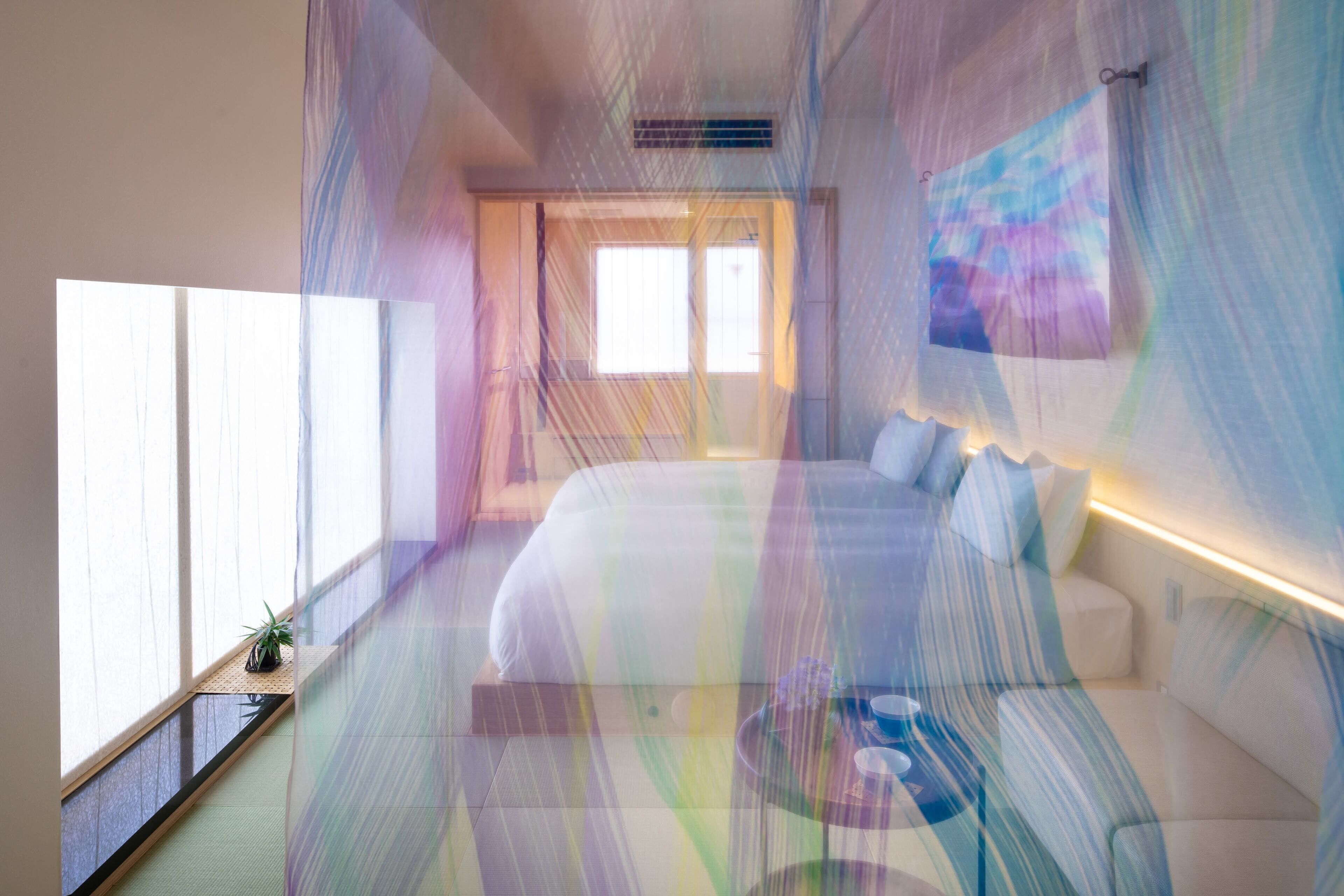 Habitación de hotel moderna con una cama grande, mesitas de noche y vistas al exterior.
