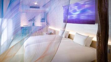 Una habitación de hotel moderna con cama, mesitas de noche y un amplio ventanal con vistas.