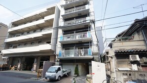 A multi-story residential building with balconies, a garage, and a bicycle parked outside. - Apartment Y Mell Theater Resort (Osaka)