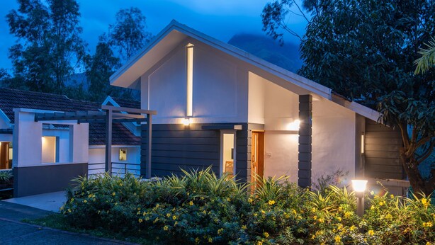 Ein modernes Haus mit geneigtem Dach, einer Veranda und einem gut beleuchteten Eingang.