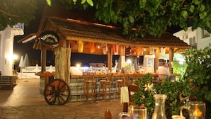 A rustic outdoor bar with a wooden structure, a sign reading "STRONGBOW," and a cart with wheels. - Julia Apartments (Rethymno)