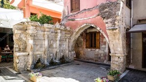 An outdoor courtyard with stone walls, a wooden door, and potted plants. - Julia Apartments (Rethymno)