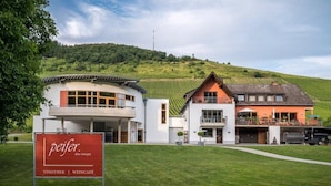En moderne bygning med et skilt, der viser teksten "peifer dein weingut" og "VINOTHEK | WEINCafé".