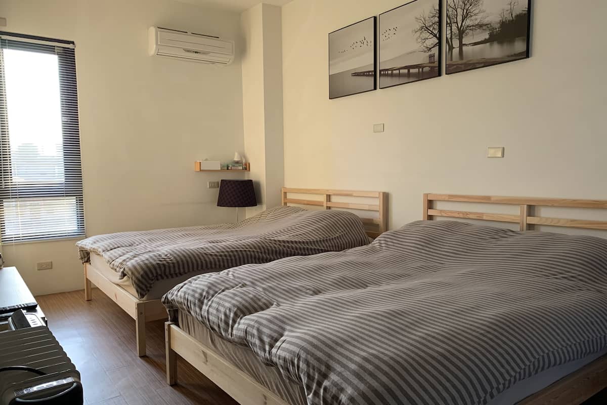 Un dormitorio con dos camas, un escritorio y una ventana con persianas.