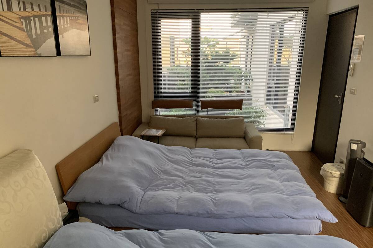 Un dormitorio con una cama grande, un sofá y una ventana con persianas.