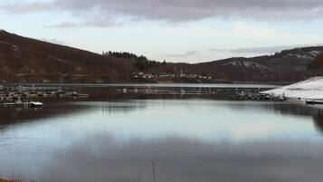 Un lac paisible, bordé de quais et de bateaux, entouré de collines et d’un petit village.