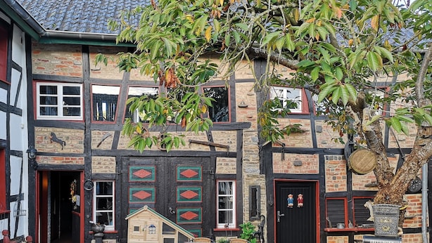 A traditional European building with a wooden facade, multiple windows, and a small wooden playhouse. - Ferienhof Schmickerath (Simmerath)