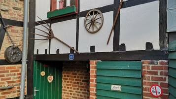 A traditional half-timbered building with a green door, a window with checkered curtains, and a no-smoking sign.