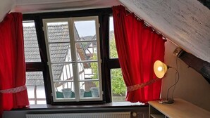 Una camera da letto accogliente in mansarda, con un letto, una scrivania e un termosifone.