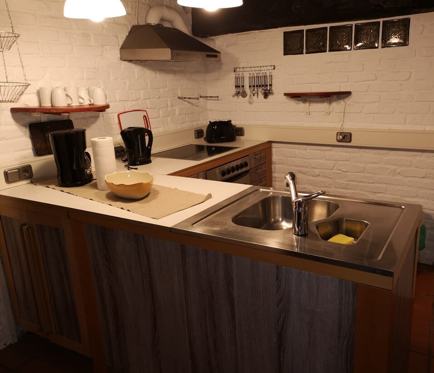 Una cocina con un lavaplatos de acero inoxidable, armarios de madera, una cafetera y un hervidor sobre la encimera.