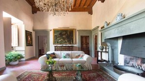Una sala de estar acogedora con un sofá blanco, una mesa de centro de cristal, una chimenea y una araña.