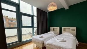 Una habitación con dos camas, un ventanal grande y vistas al exterior.