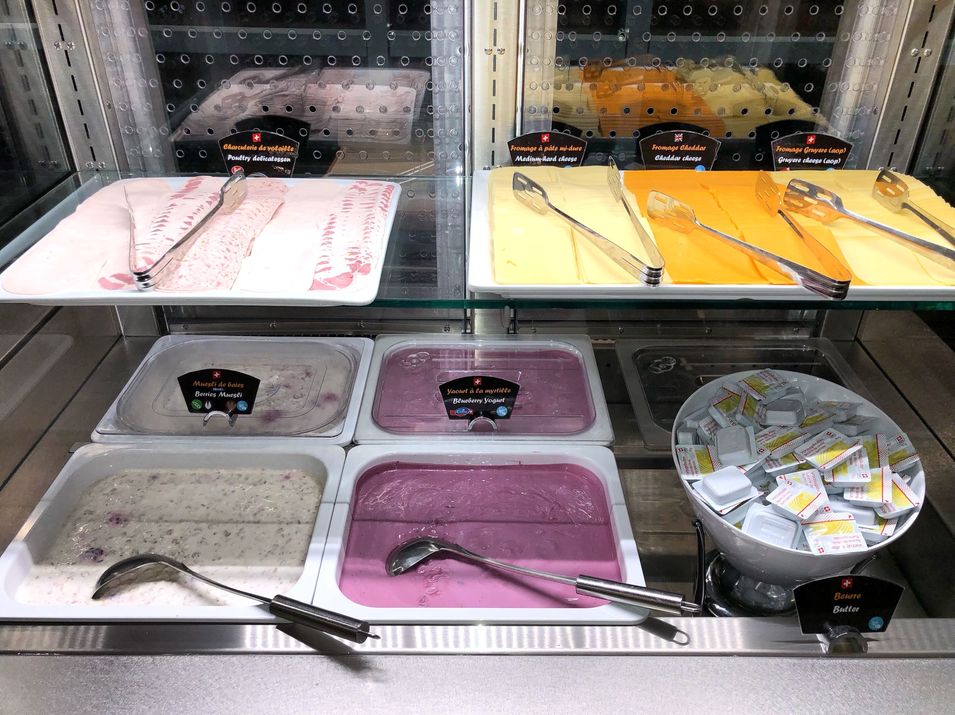 A cheese and yogurt display with various types of cheese and yogurt in separate containers.