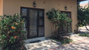 A building with a beige facade, a glass door entrance, and two lantern-style lights above the door. - Havilla Guest House (Gaborone)