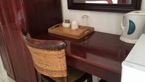 A wooden table with a tray holding a mug, a small container, and a glass pitcher. A wicker chair is positioned in front of the table. - Havilla Guest House (Gaborone)