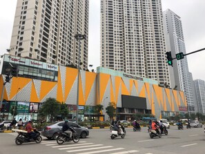 Une rue animée en plein centre-ville, bordée d’immeubles de grande hauteur, avec un centre commercial Vincom et divers magasins, dont un magasin CTV.