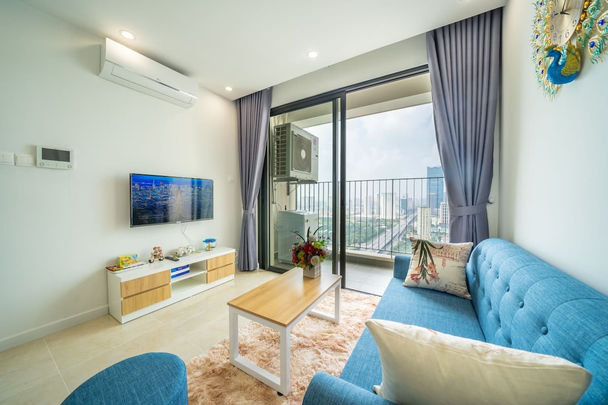 A modern living room with a sofa, a coffee table, a TV, and a balcony with a city view.