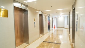 A modern hallway with elevators, a fire extinguisher, and a clean, polished floor.
