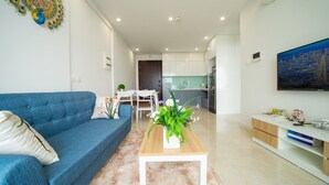A modern living room with a blue sofa, a wooden coffee table, and a white rug.