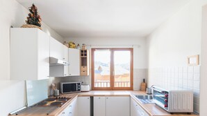 Een kleine keuken met witte kastjes, een magnetron, een broodrooster en een fornuis.