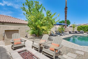A poolside area with Adirondack chairs, a fire pit, and a palm tree. - Enjoy Luxury By Tennis/Coachella/Stagecoach (Indian Wells)