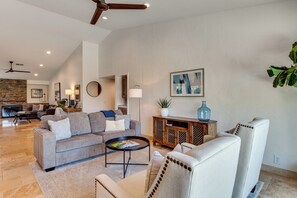 A spacious living room with a grey sofa, a coffee table, and a fireplace. - Enjoy Luxury By Tennis/Coachella/Stagecoach (Indian Wells)