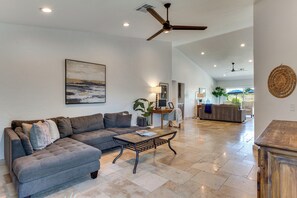 A spacious living room with a grey sectional sofa, a coffee table, and a ceiling fan.
