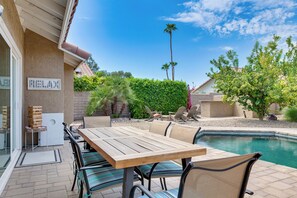 An outdoor patio with a pool, a wooden table, and chairs. - Enjoy Luxury By Tennis/Coachella/Stagecoach (Indian Wells)