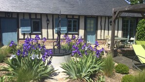 A traditional building with a stone facade, a wooden deck, and a garden with purple flowers. - Le Clos-Masure de Béatrice, a refined home overlooking a beautiful garden. (MONTREUIL EN CAUX)