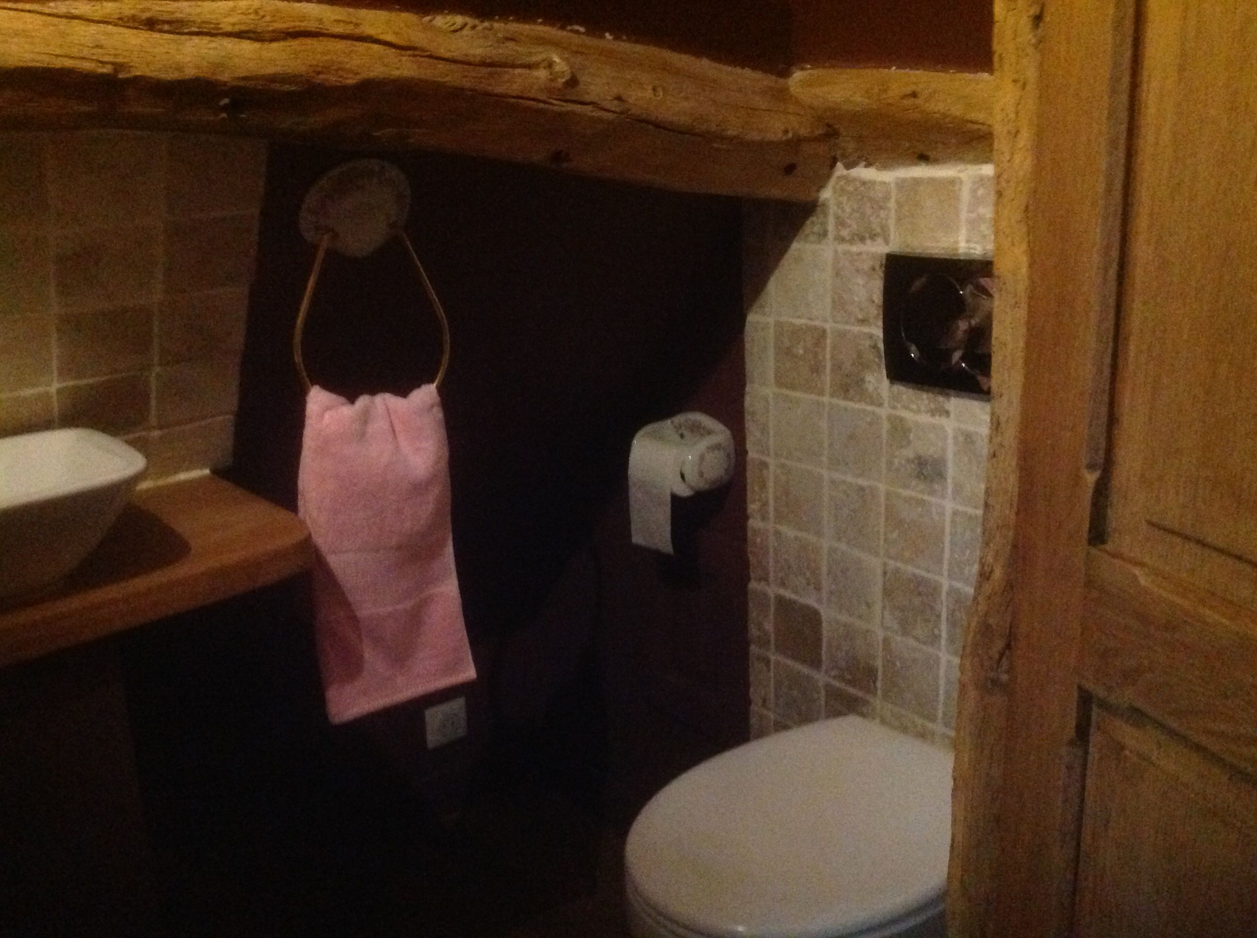 Ein kleines Badezimmer mit einem Holzboden, einem weißen Waschbecken, einer Toilette und einem Handtuch an einem Haken.