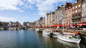 A harbor with boats docked along the waterfront, surrounded by historic buildings with various architectural styles. - Le Clos-Masure de Béatrice, a refined home overlooking a beautiful garden. (MONTREUIL EN CAUX)