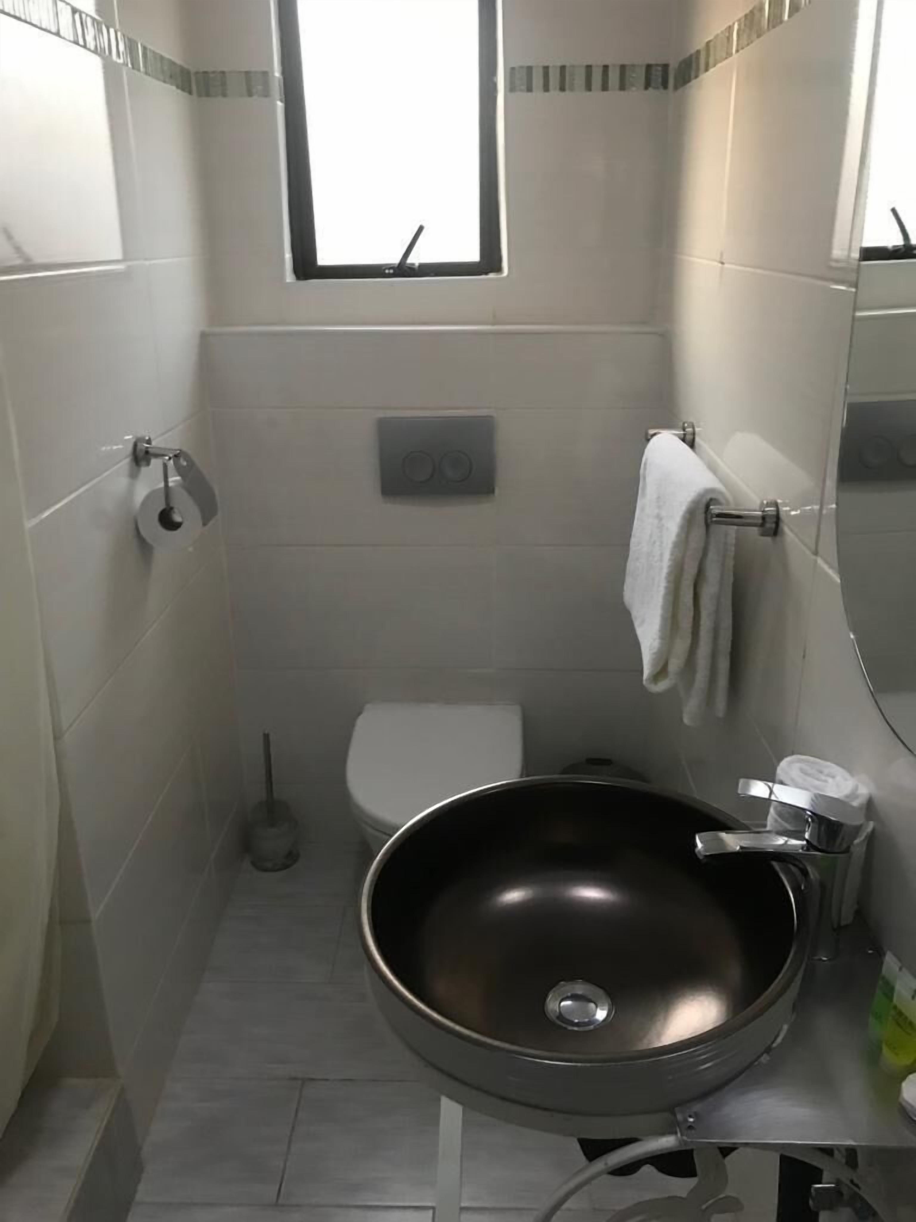 Une petite salle de bain comprenant des toilettes, un lavabo, un miroir et un porte-serviettes.