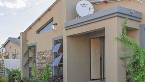 Una casa moderna de dos pisos, con antena parabólica, fachada de piedra y entrada pavimentada.