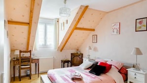 A bedroom with a sloped ceiling, a bed with pink bedding, a desk with a chair, and a window. - Room In A House Full Of Life (Saint-Rémy-lès-Chevreuse)