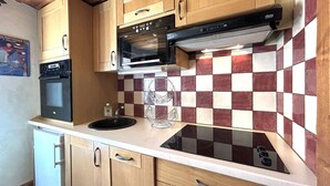Une cuisine compacte avec des meubles en bois, un four encastré, un four à micro-ondes et un crédence à carreaux.