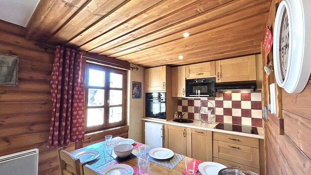 Une cuisine de taille réduite avec des murs en bois, un dosseret à carreaux et des appareils électroménagers simples.
