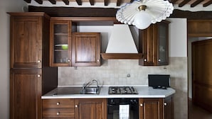 A kitchen with wooden cabinets, a sink, a stove, and a television.