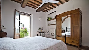 A bedroom with a bed, wooden wardrobe, and a balcony door.