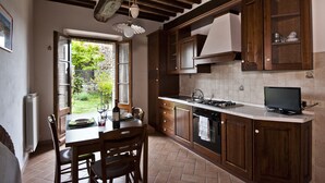 A kitchen with wooden cabinets, a stove, and a dining table with chairs.