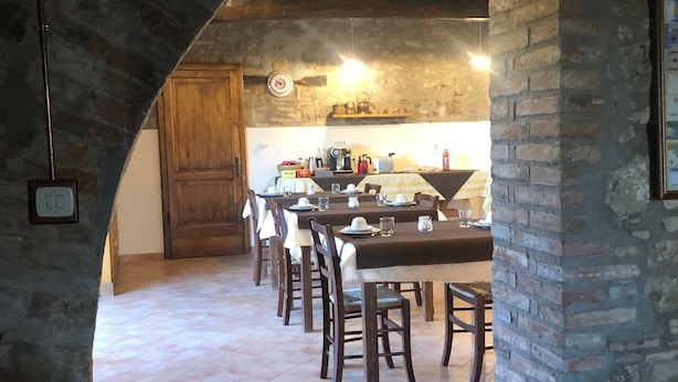 A rustic dining area with a stone archway, wooden tables, and chairs.