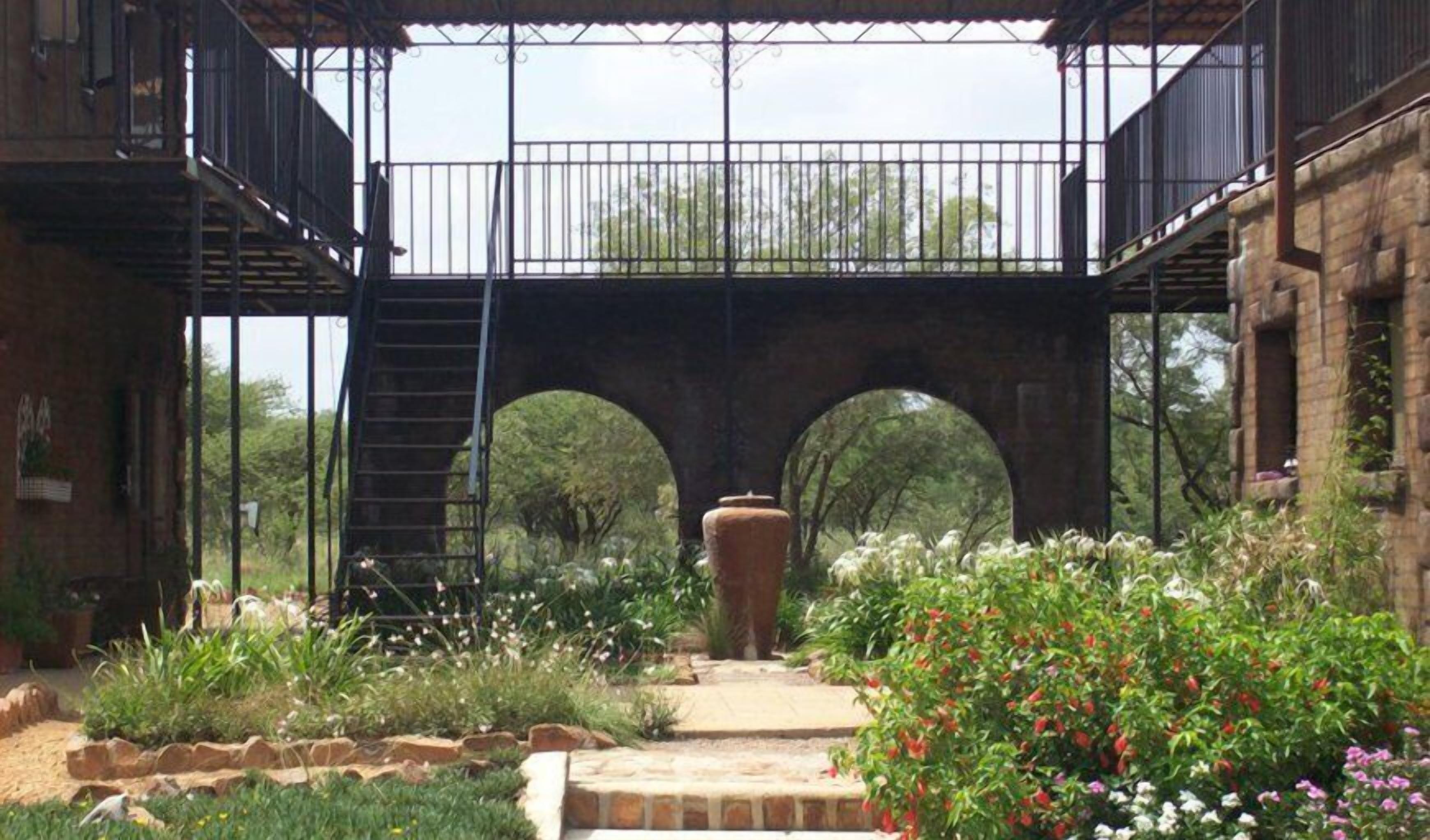 A courtyard with a brick building, a metal staircase, and a bridge.