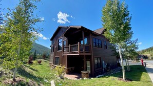 A two-story wooden house with a balcony, surrounded by trees and a mountain in the background. - Modern 3BR Mountain Retreat in North Keystone (Keystone)