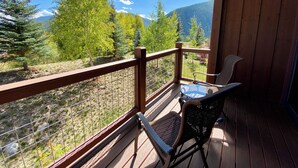 A wooden deck with a table and chairs, overlooking a mountainous landscape with trees and a clear sky. - Modern 3BR Mountain Retreat in North Keystone (Keystone)
